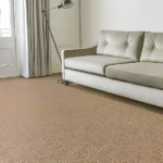 Bright living room with a cream sofa, floor lamp, curtains, and beige jute carpet.