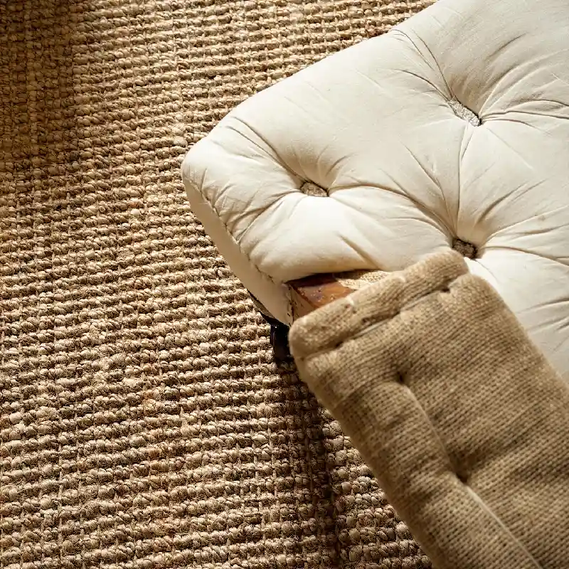 Close-up of a natural woven jute carpet texture paired with upholstered furniture.