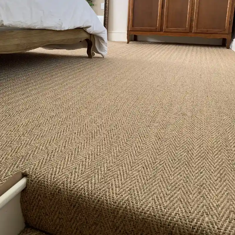 Herringbone-patterned sisal carpet on a bedroom floor.