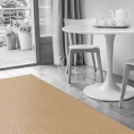 Minimalist dining area with a beige patterned rug, white table and chairs, and gray curtains.