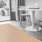Minimalist dining area with a beige textured rug, white table and chairs, and gray curtains
