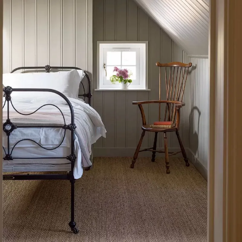 Natural woven jute carpet flooring in a traditional bedroom with a metal bed