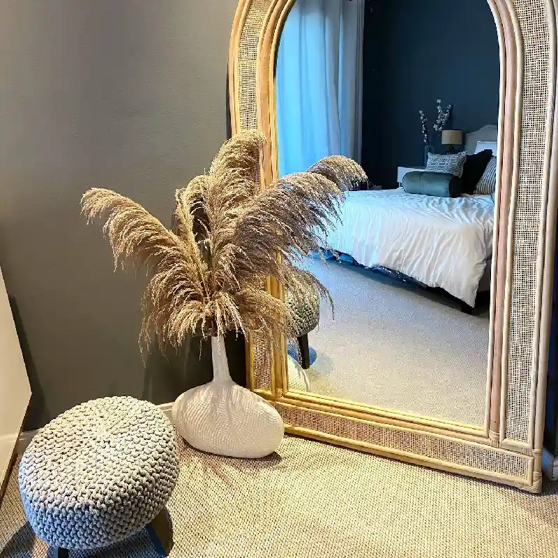 Textured natural jute carpet and flooring featured beneath a large rattan-framed mirror