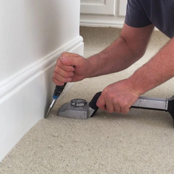 Trimming beige wall to wall carpet along baseboard